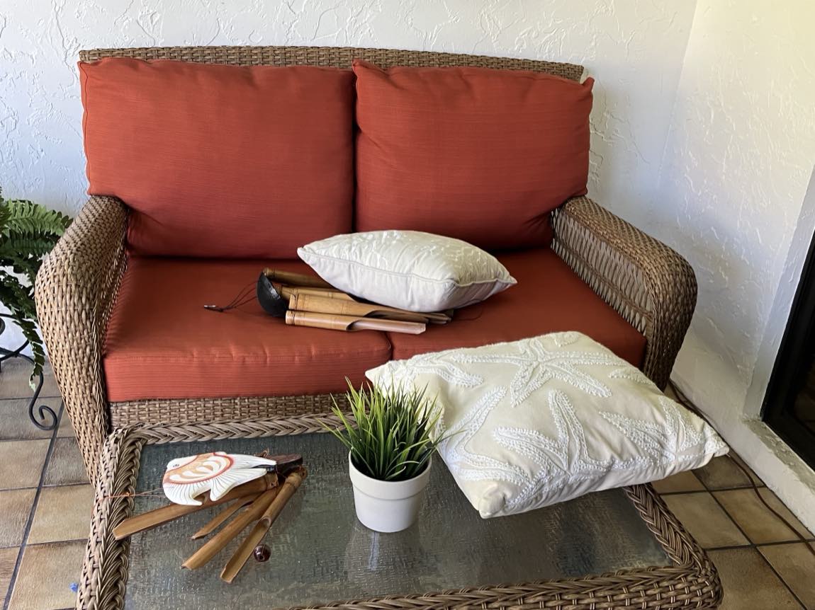 Wicker patio loveseat reupholstered with new terracotta cushions and decorative pillows